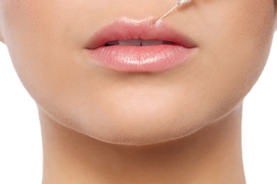 Photo of Young woman getting lips injection on white background, closeup. Cosmetic surgery