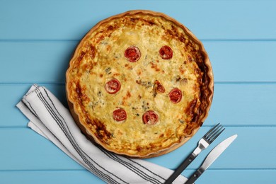 Photo of Delicious quiche with cheese and tomatoes on light blue wooden table, flat lay