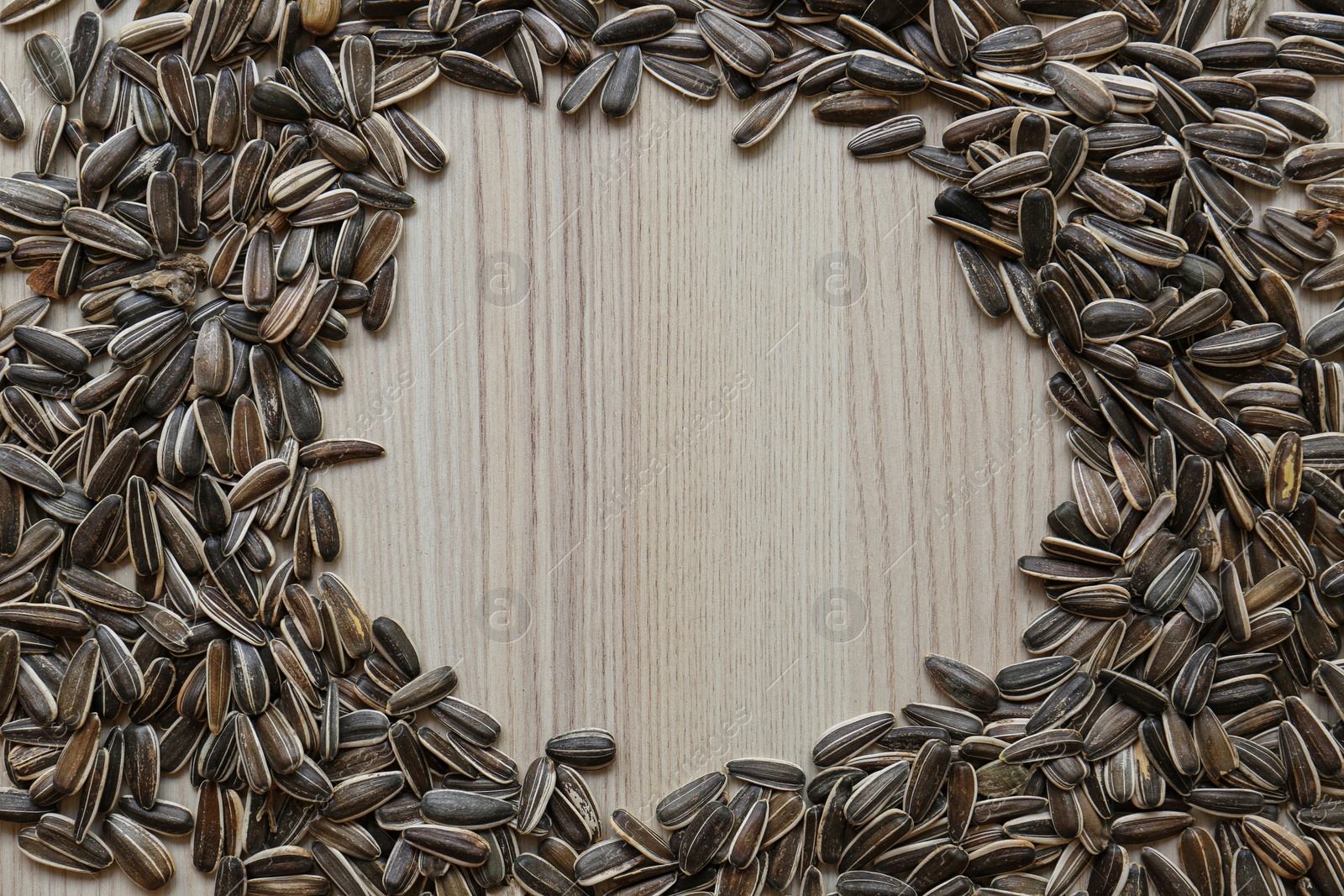 Photo of Frame of sunflower seeds on wooden table, flat lay. Space for text