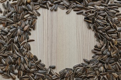 Photo of Frame of sunflower seeds on wooden table, flat lay. Space for text