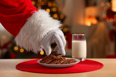 Merry Christmas. Santa Claus taking cookies from plate on table in room, closeup
