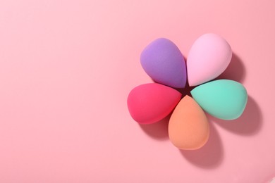 Photo of Many different makeup sponges on pink background, top view. Space for text
