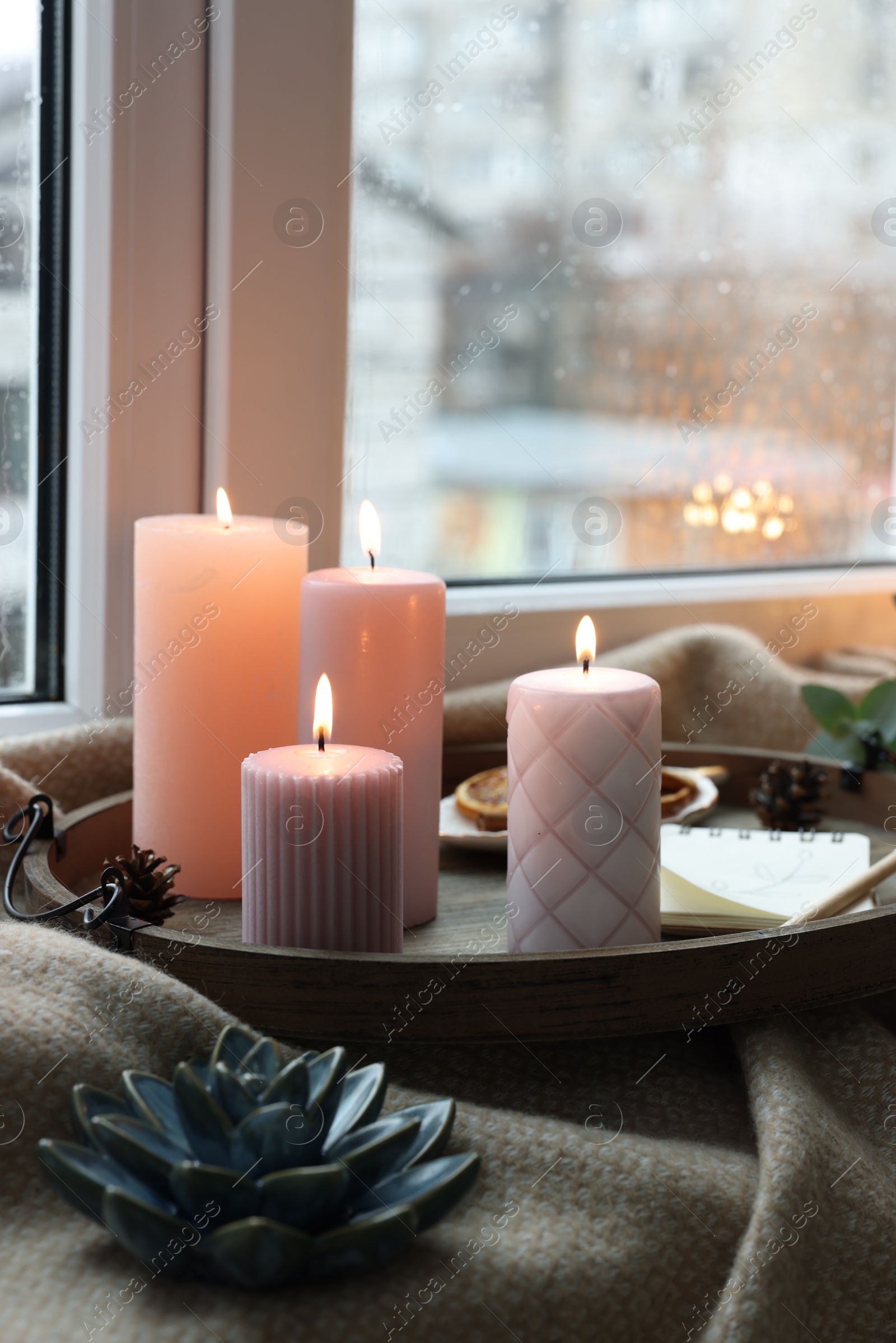 Photo of Tray with burning wax candles and decor on window sill indoors