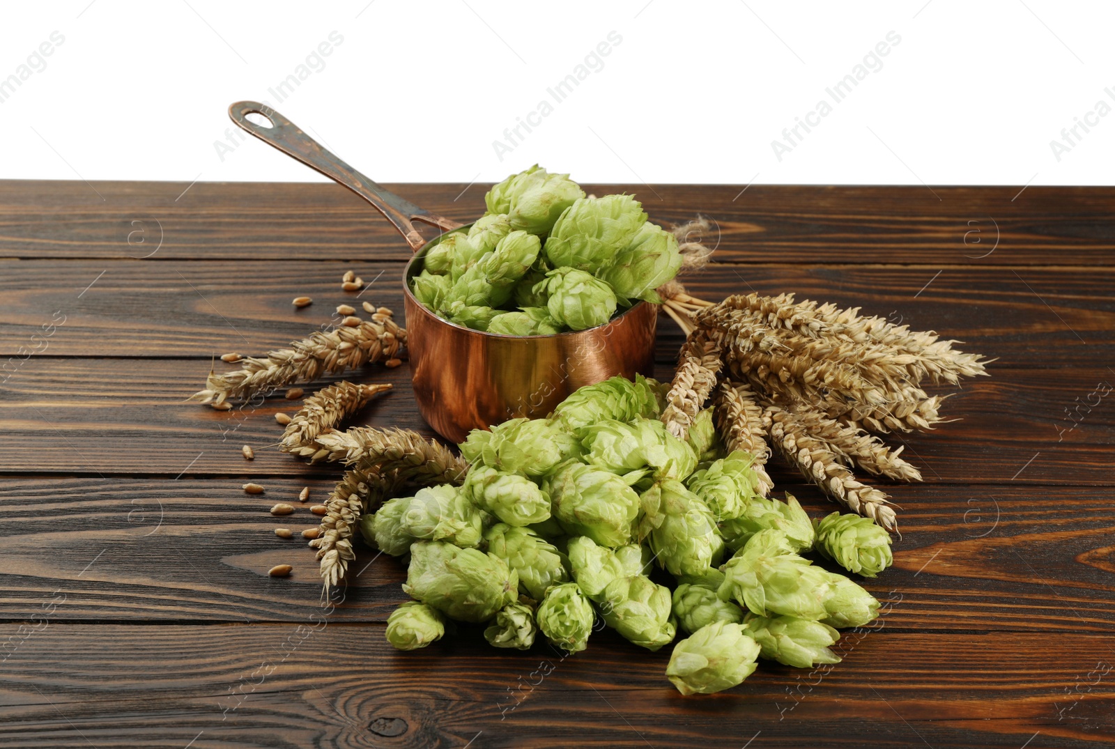 Photo of Fresh hop flowers and wheat ears on wooden table against white background