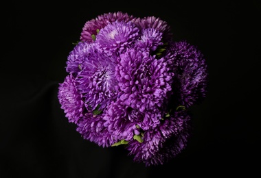 Bouquet of beautiful purple asters on black background, top view. Autumn flowers