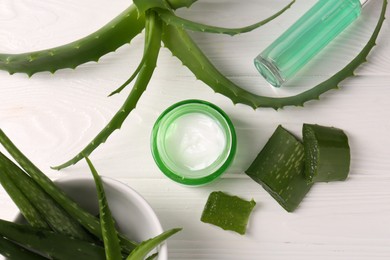 Different cosmetic products and cut aloe vera leaves on white wooden table, flat lay