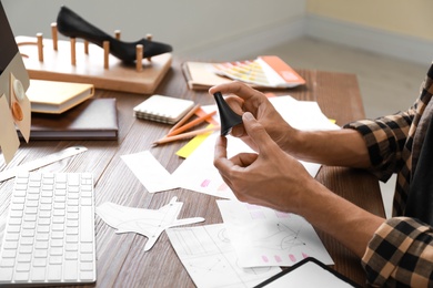 Male designer working at wooden table, closeup