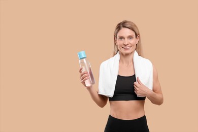 Photo of Athletic woman with bottle of water and white towel on beige background, space for text