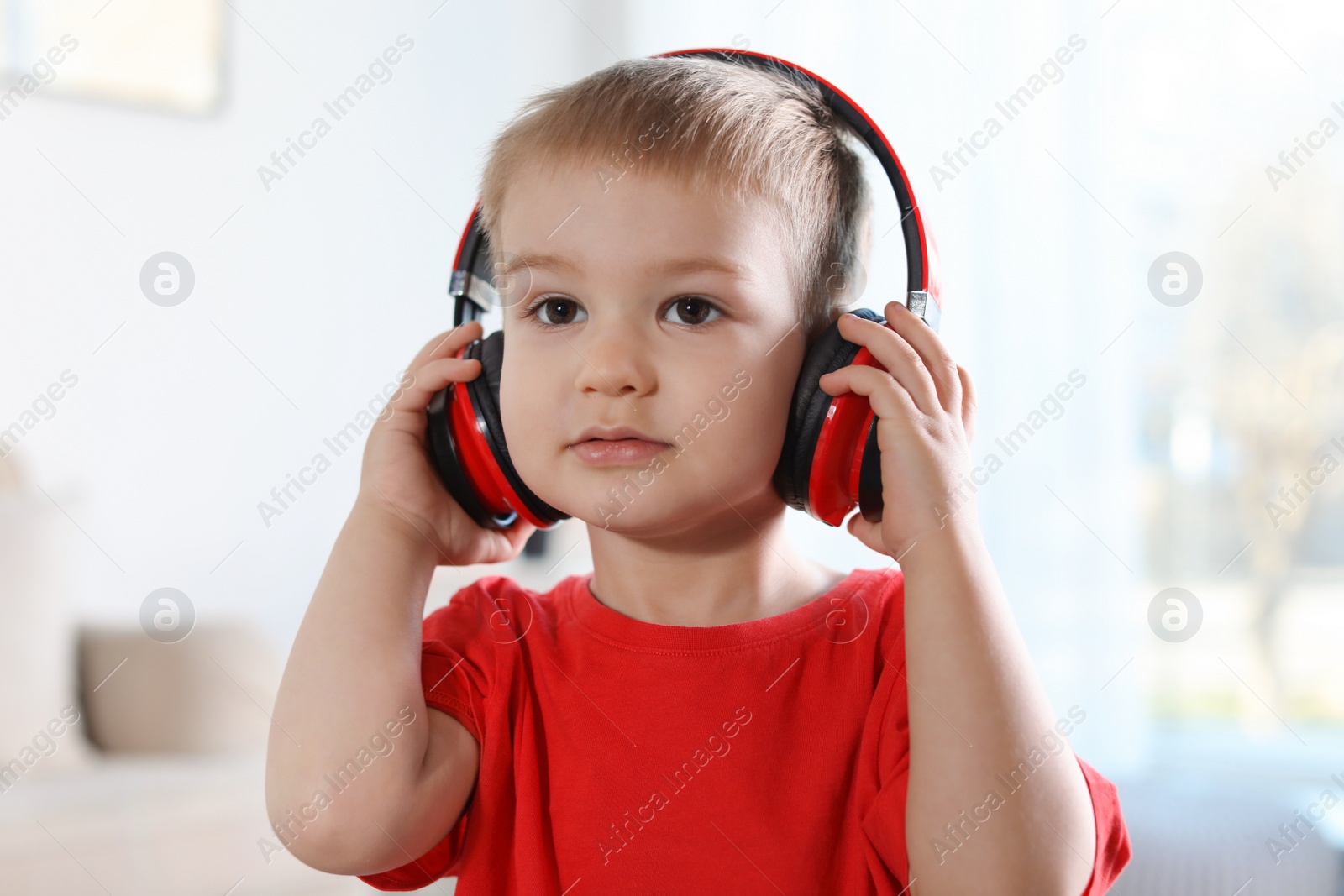 Photo of Cute child listening to music with headphones indoors