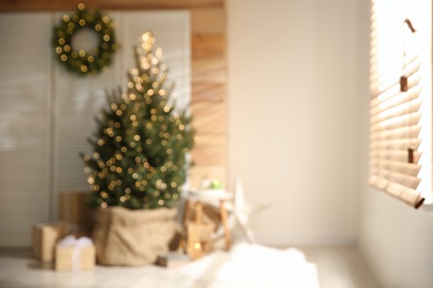 Blurred view of spacious room with Christmas tree and wreath. Interior design