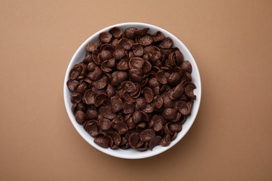 Photo of Breakfast cereal. Chocolate corn flakes in bowl on brown table, top view