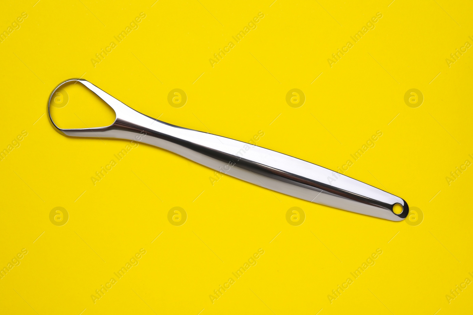 Photo of Metal tongue cleaner on yellow background, top view