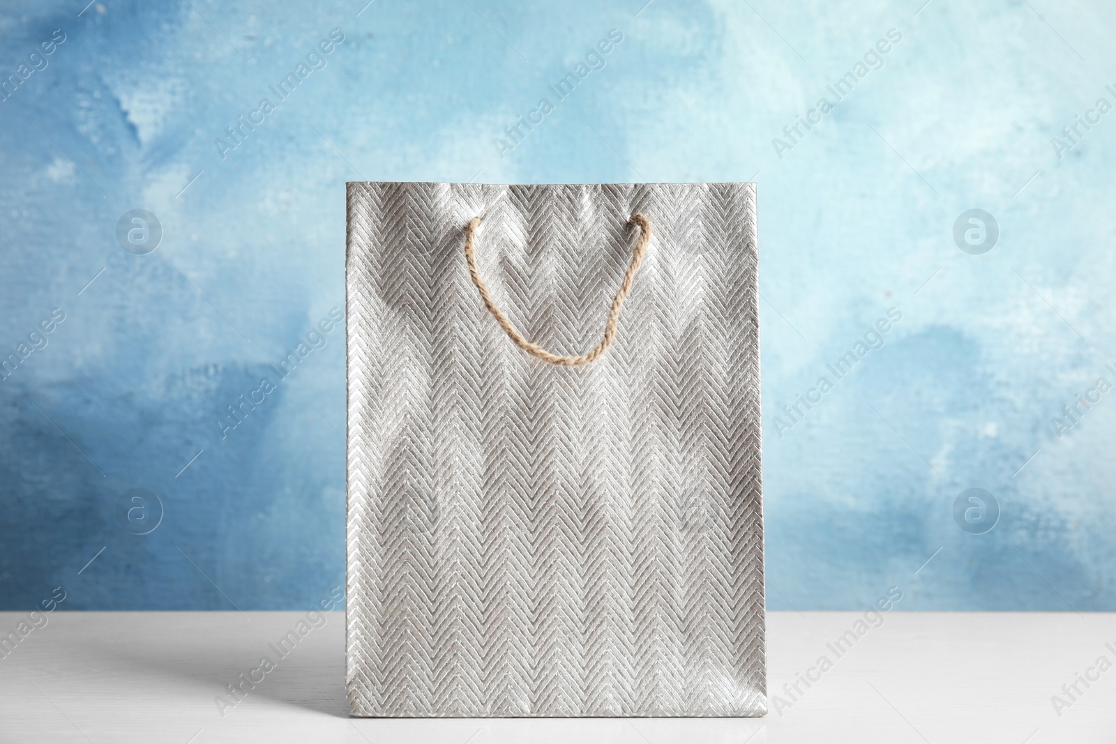 Photo of Silver shopping paper bag on white table