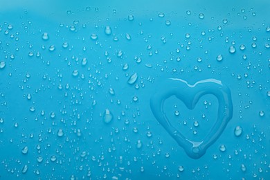 Photo of Heart shape of water and drops on light blue background, top view