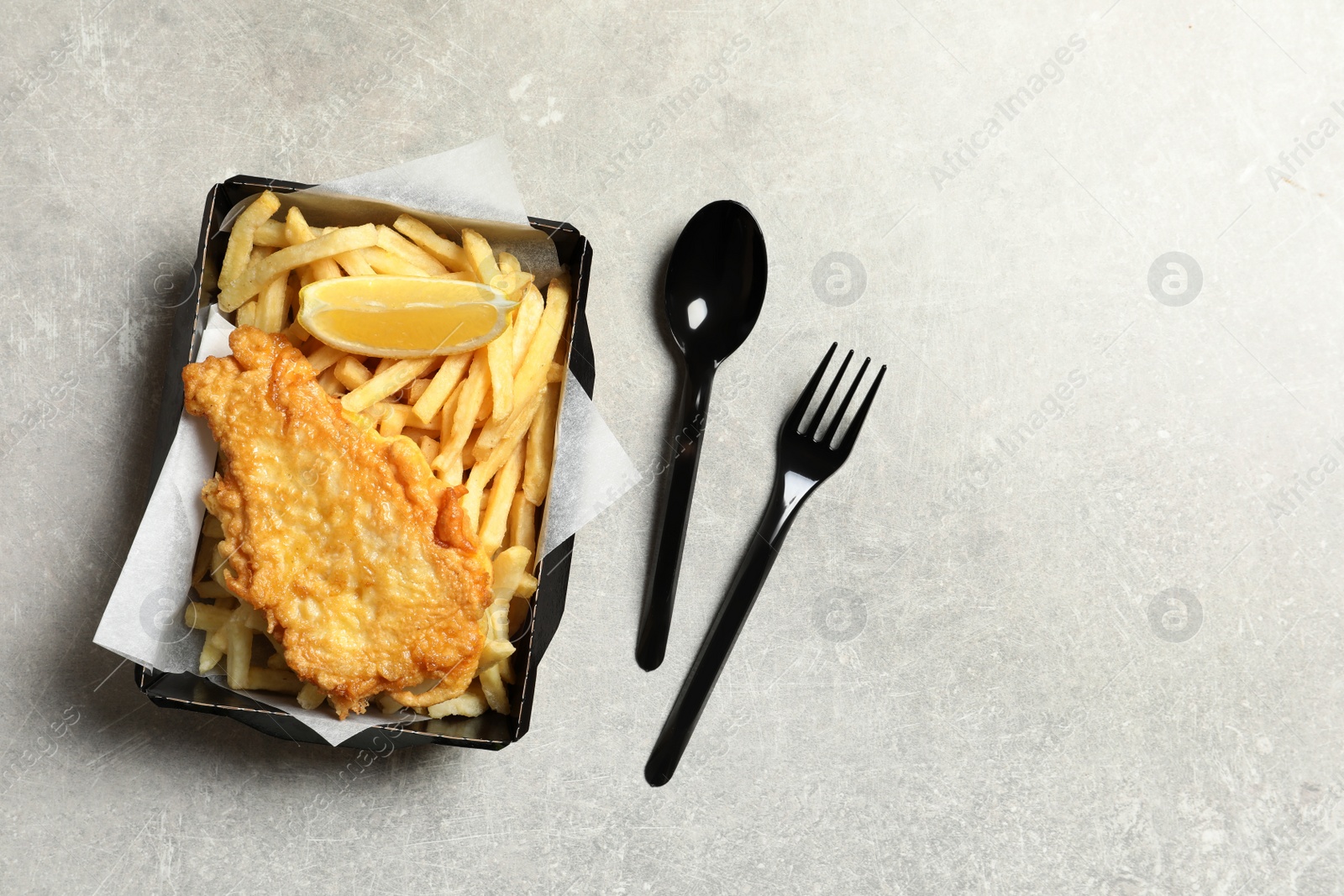 Photo of Disposable container with British Traditional Fish and potato chips on grey background, top view. Space for text