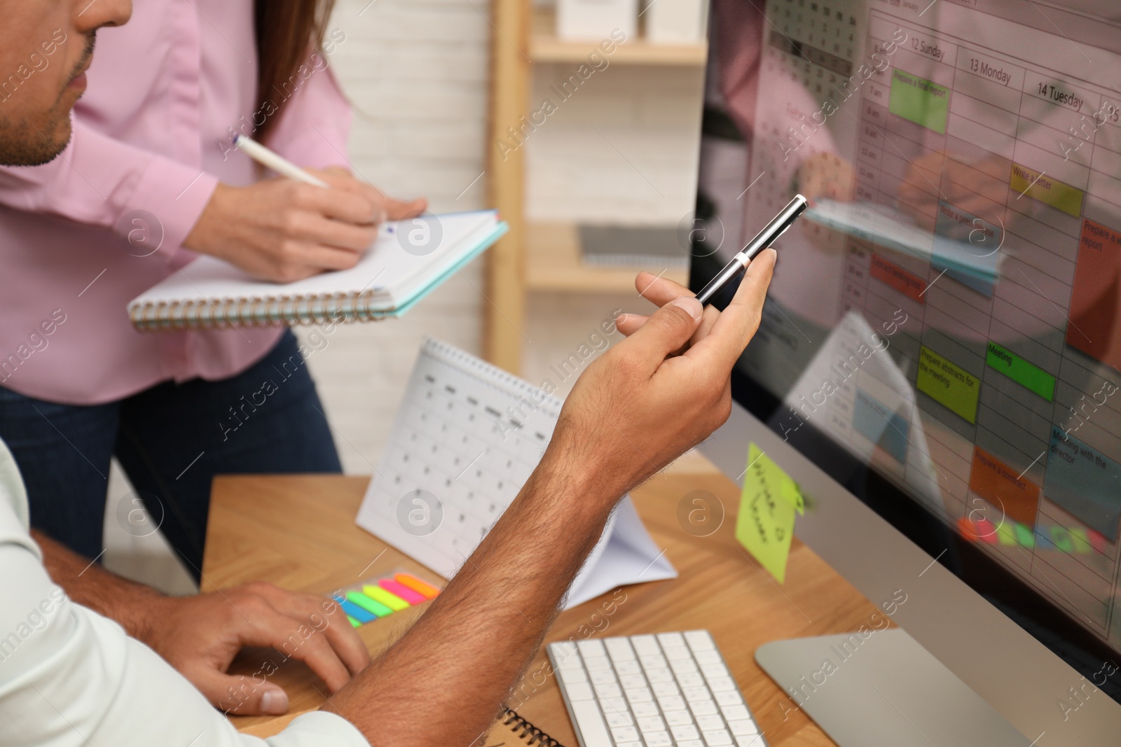 Photo of Colleagues working with calendar app on computer in office, closeup