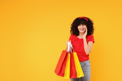 Photo of Happy young woman with shopping bags on yellow background