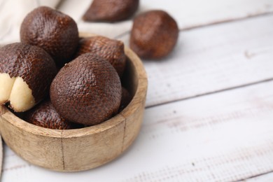 Fresh salak fruits in bowl on white wooden table, closeup. Space for text