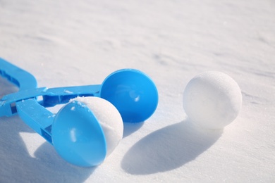 Photo of Snowballs and light blue plastic tool outdoors on winter day, closeup