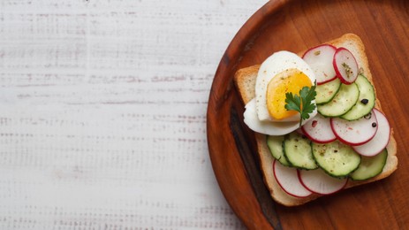 Photo of Tasty sandwich with boiled egg, radish and cucumber on white wooden table, top view. Space for text