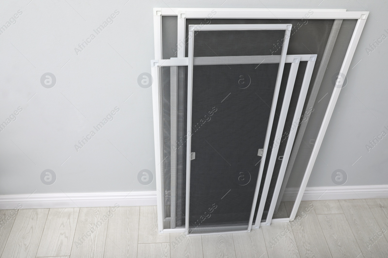 Photo of Set of window screens near light grey wall indoors, above view. Space for text