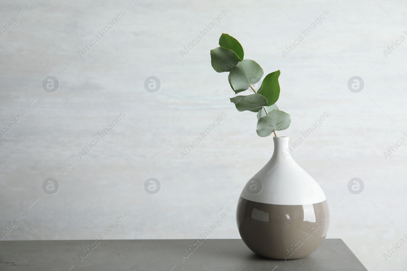 Photo of Vase with eucalyptus branch with fresh leaves on table