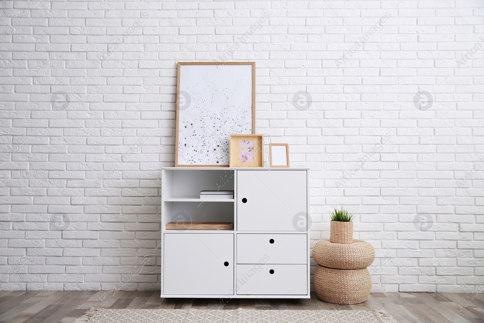 Photo of Modern white cabinet near brick wall in room. Interior design