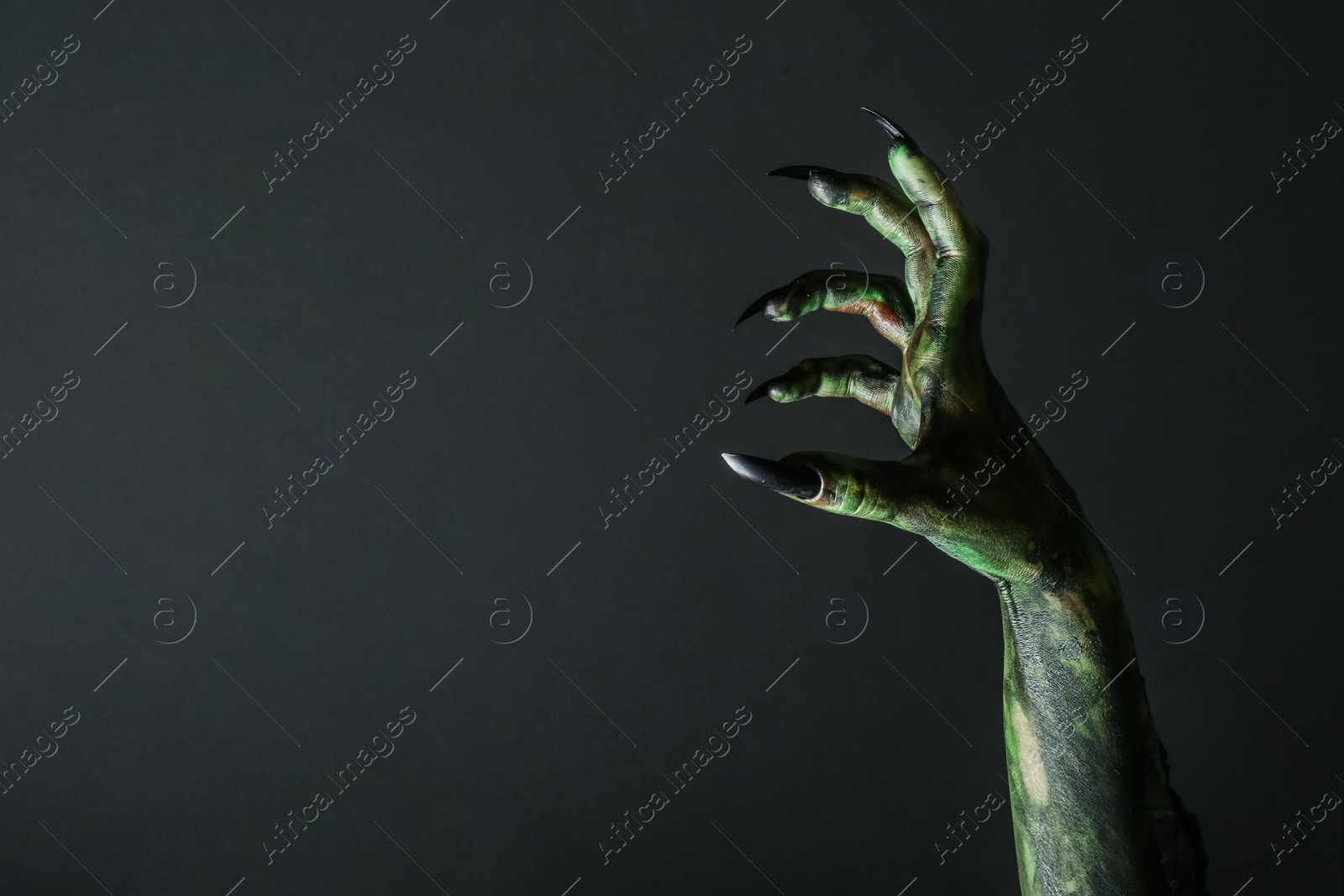 Photo of Scary monster on black background, closeup of hand with space for text. Halloween character