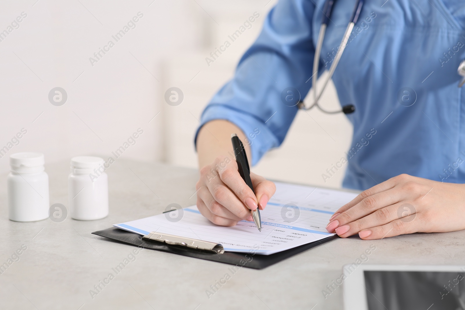 Photo of Doctor filling patient's medical card at table in clinic, closeup