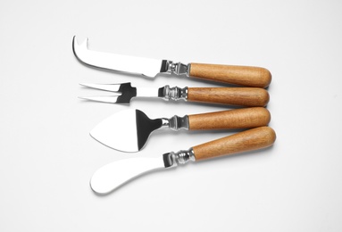 Cheese knives and fork on white background, top view