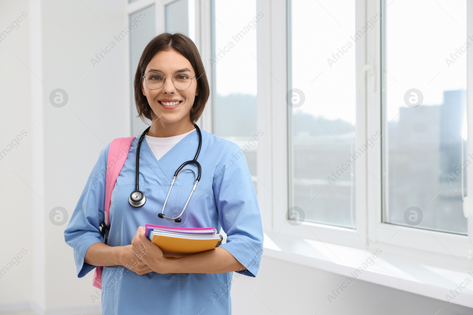 Photo of Smart medical student with notebooks in college hallway, space for text