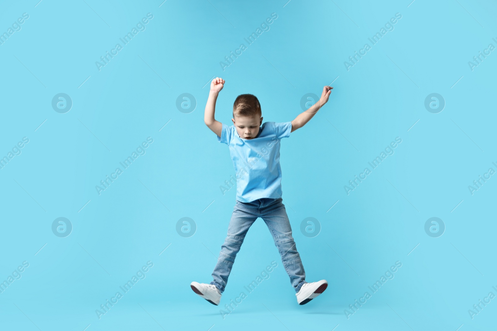 Photo of Happy little boy dancing on light blue background