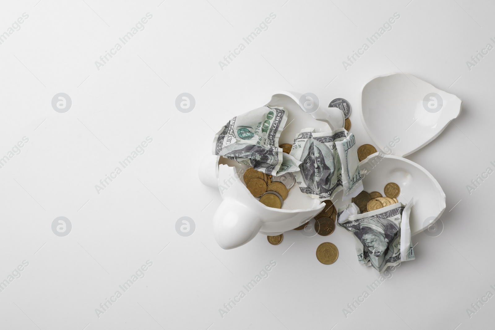 Photo of Broken piggy bank with coins and banknotes on white background