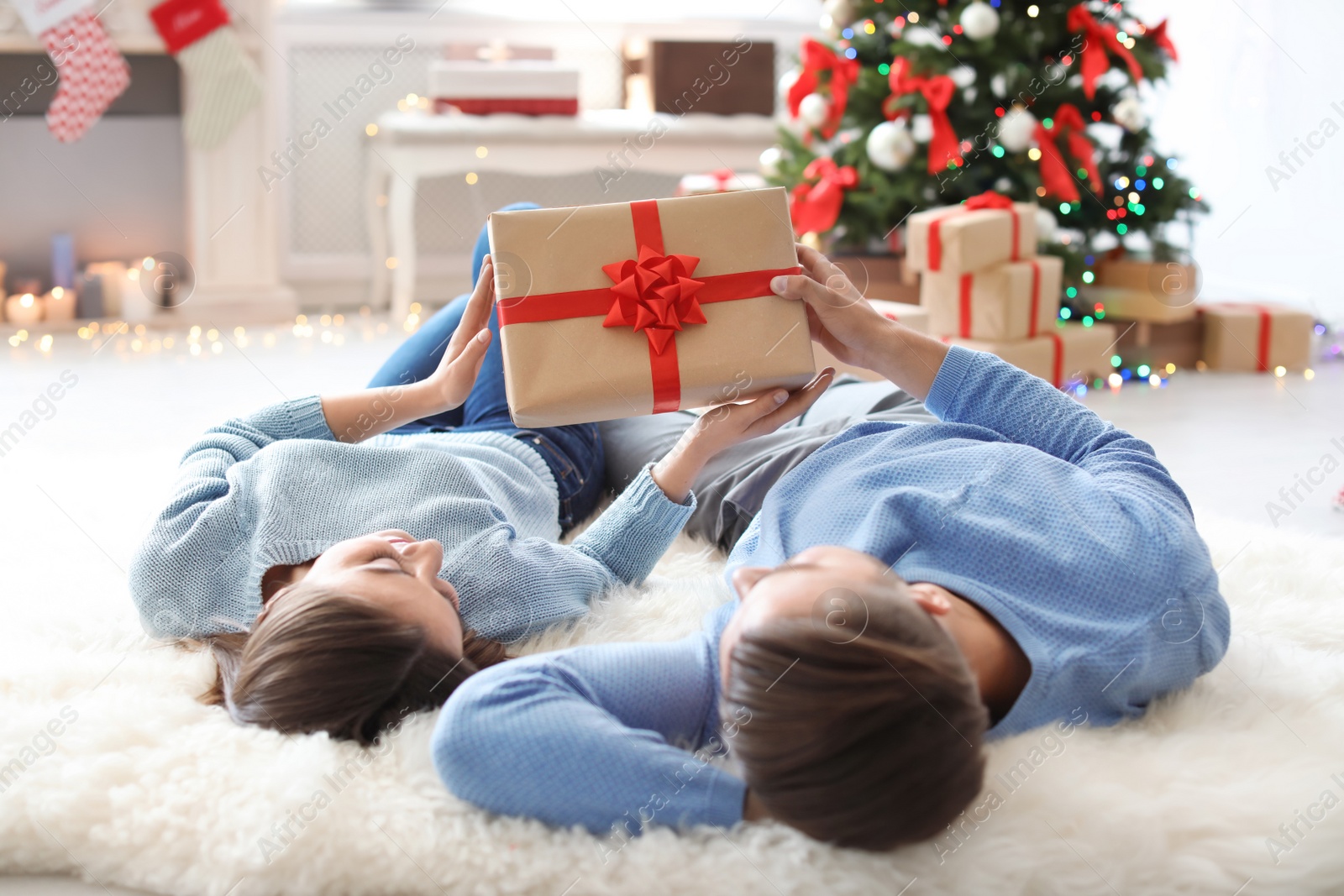 Photo of Young couple with Christmas gift at home