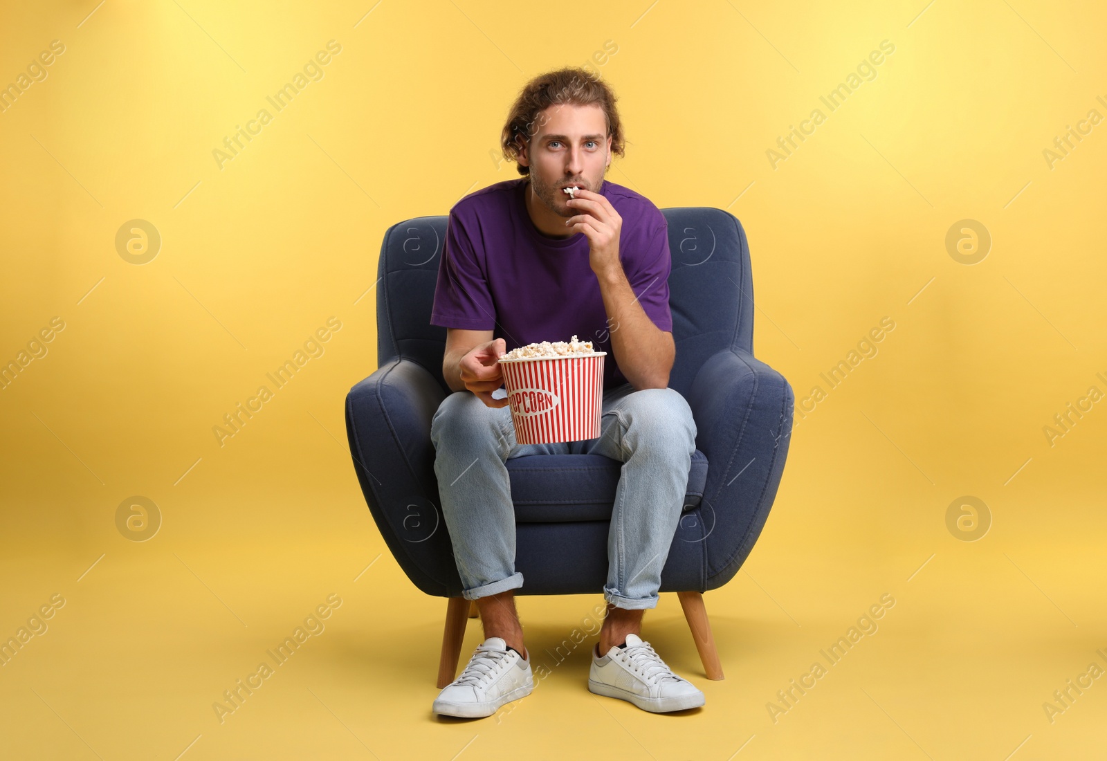 Photo of Man with popcorn sitting in armchair during cinema show on color background