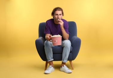 Photo of Man with popcorn sitting in armchair during cinema show on color background
