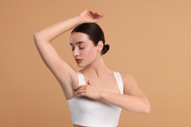 Beautiful woman showing armpit with smooth clean skin on beige background