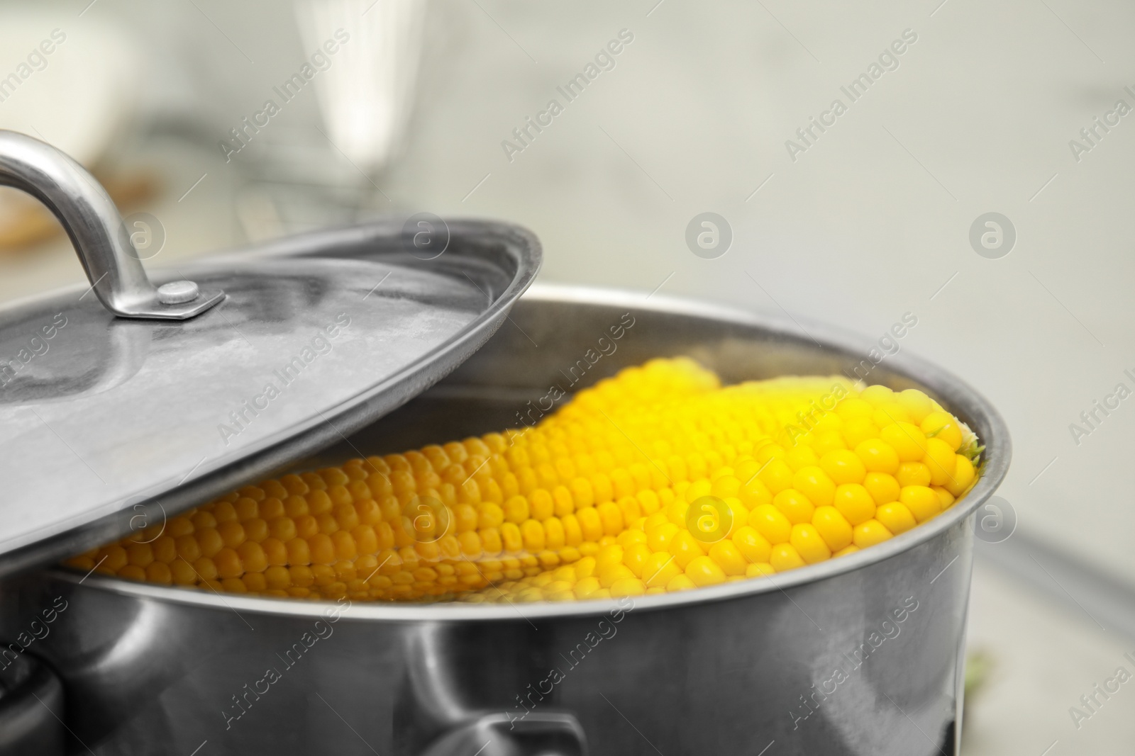 Photo of Pot with boiling corn cobs in kitchen, closeup