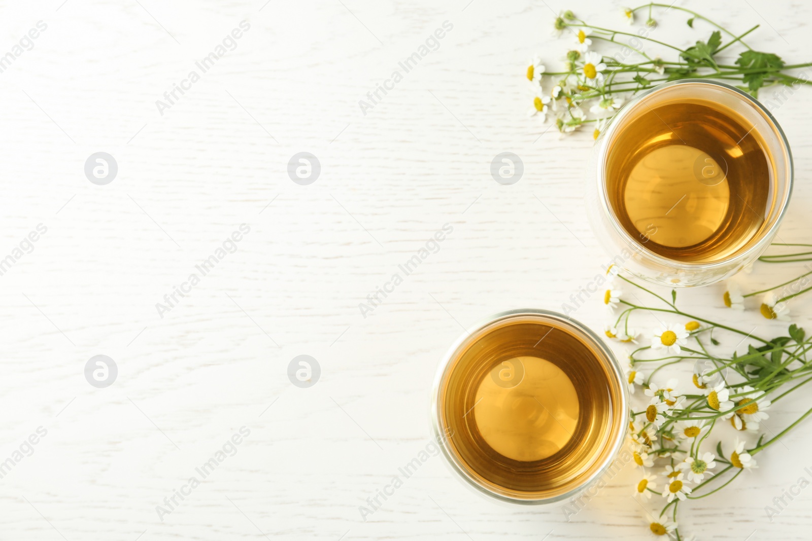 Photo of Flat lay composition with tea and chamomile flowers on white wooden table. Space for text