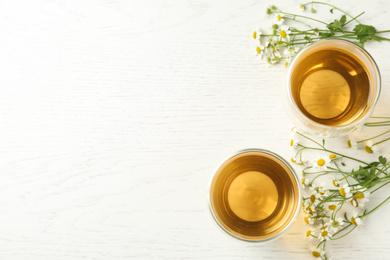 Photo of Flat lay composition with tea and chamomile flowers on white wooden table. Space for text