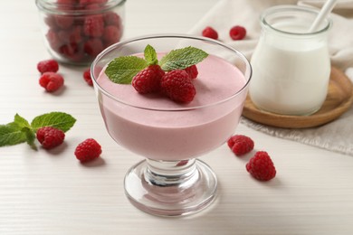 Photo of Delicious raspberry mousse with mint on white wooden table