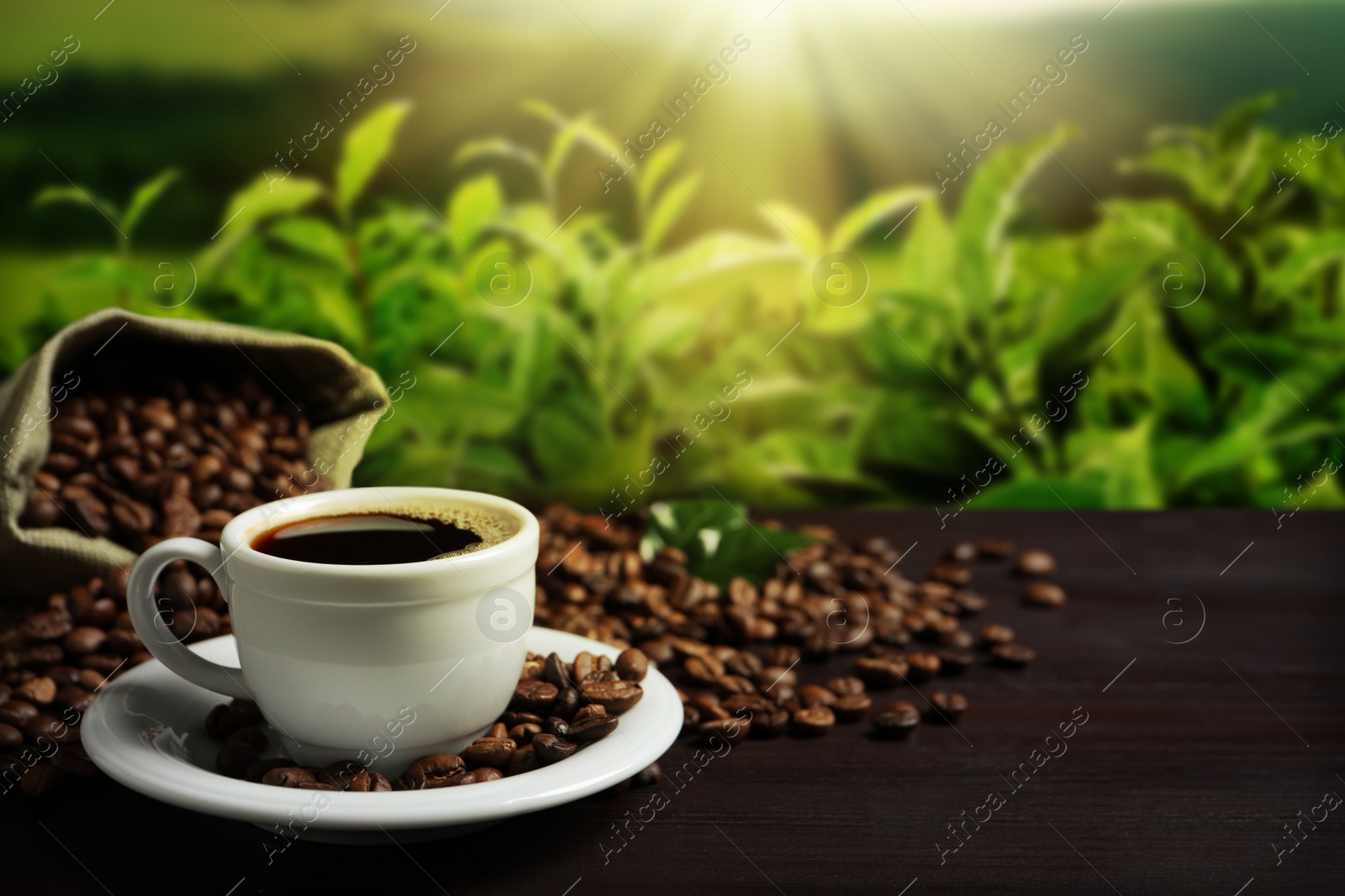 Image of Cup of aromatic hot coffee and beans on wooden table outdoors. Space for text