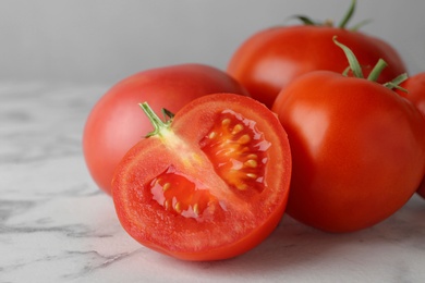 Fresh ripe whole and cut tomatoes on white marble table, closeup