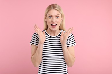 Portrait of surprised woman on pink background