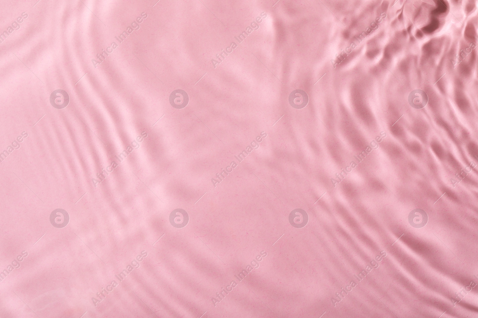 Photo of Closeup view of water with rippled surface on pink background