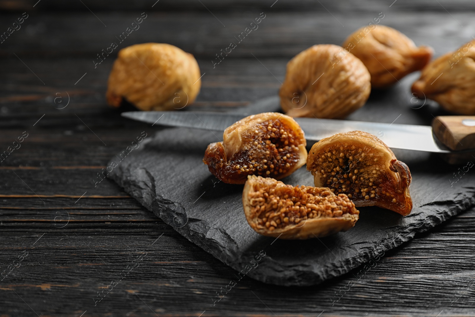 Photo of Slate plate with tasty dried figs on black wooden table, closeup. Space for text