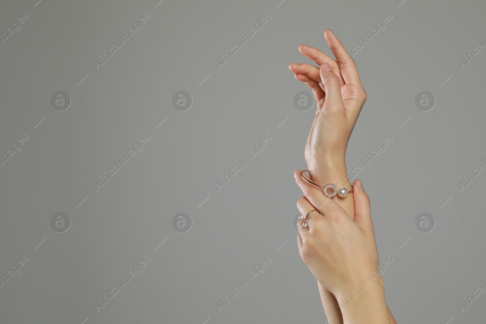 Photo of Young woman wearing elegant pearl jewelry on grey background, closeup. Space for text