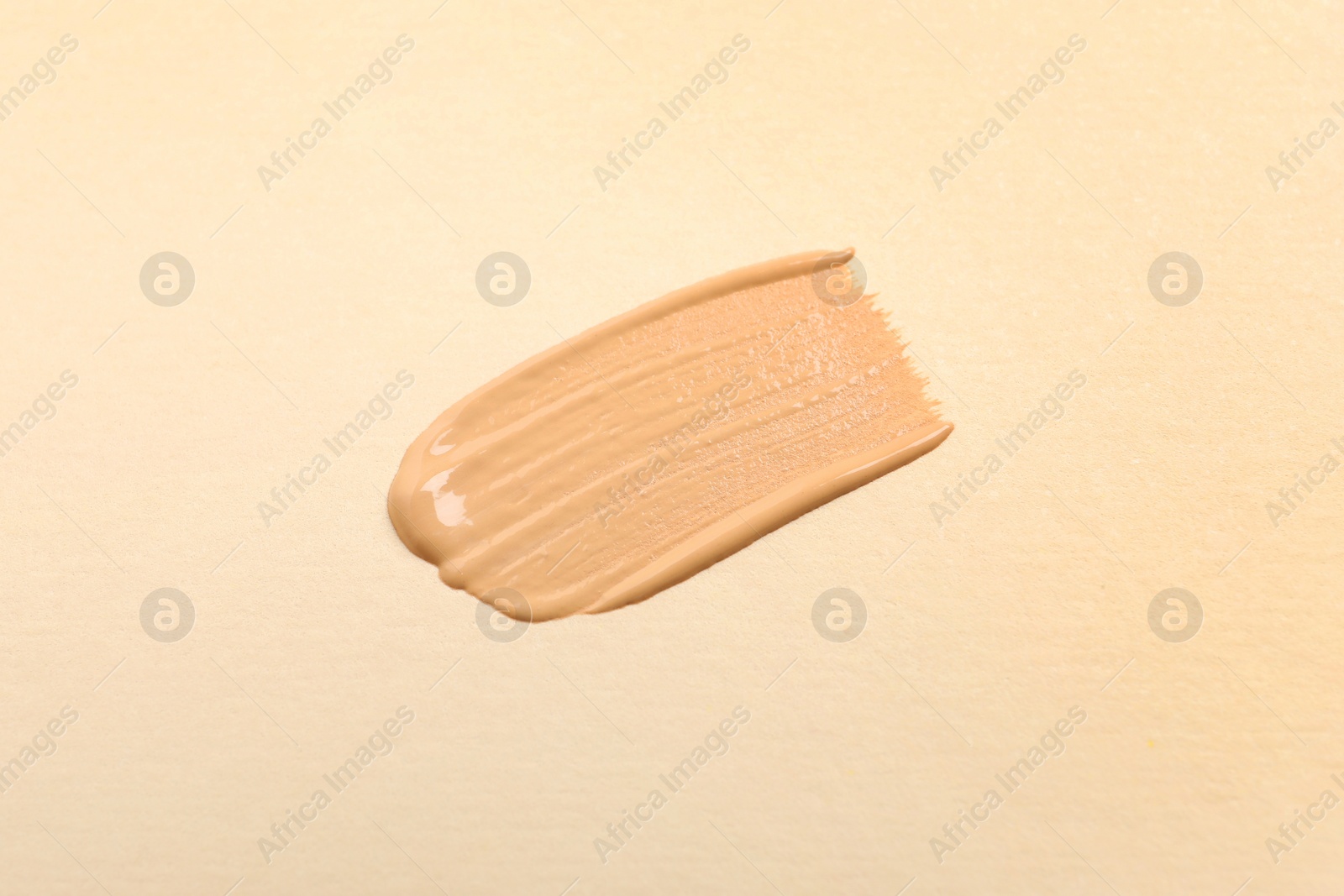 Photo of Smear of skin foundation on beige background, top view