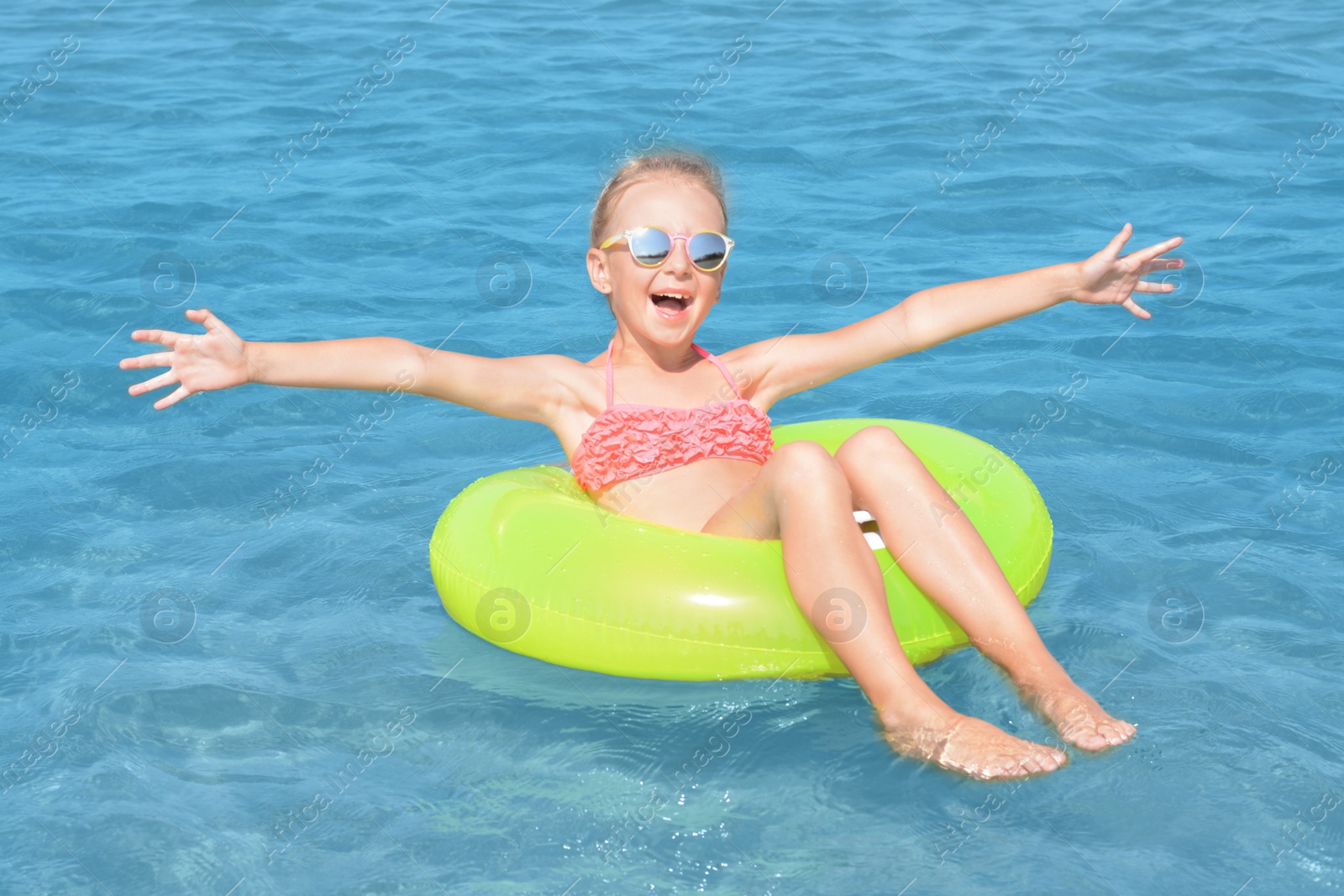 Photo of Happy little girl with inflatable ring in sea on sunny day