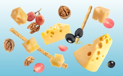 Cheese, breadsticks, grapes and walnuts falling against light blue background